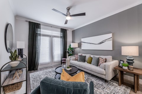 a living room with a couch and a chair and a ceiling fan